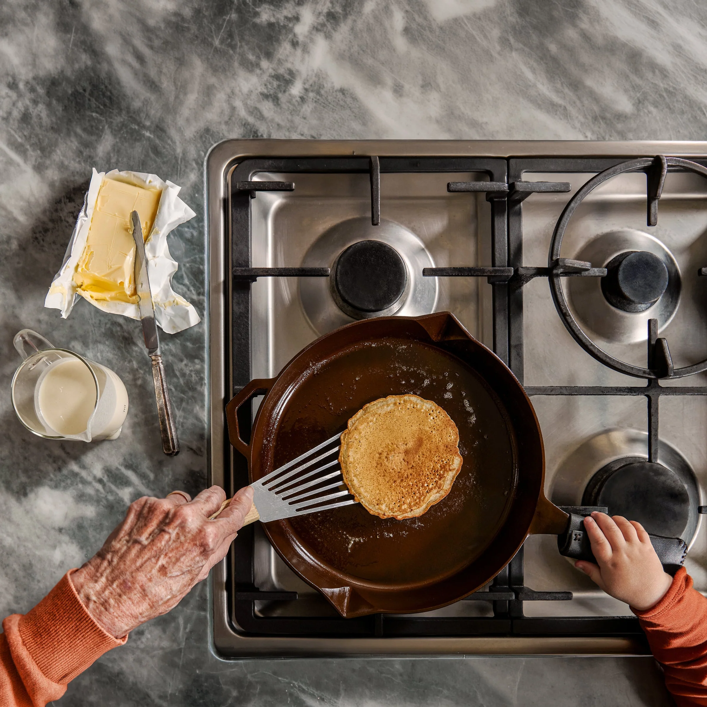 Overhead view of a pancake cooking in a cast iron pan on a gas hob